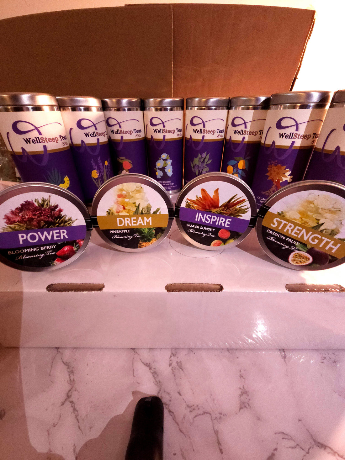 WellSteep tea blends displayed in a box on a marble counter.