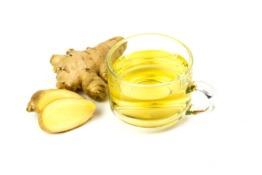 Cup of ginger turmeric green tea with fresh ginger root on a white background.